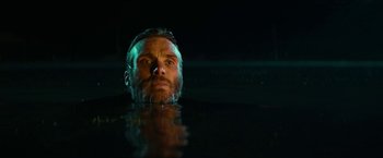 Movie still from “A Quiet Place Part II” (2020), directed by John Krasinski – A man with a goatee is in the water; Close Up shot, Low angle