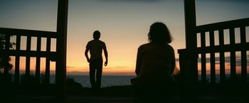 Movie still from “A Quiet Place Part II” (2020), directed by John Krasinski – A man and a woman standing on a beach at sunset; Medium shot, Low angle