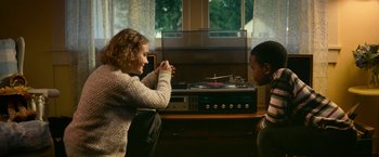 Movie still from “A Quiet Place Part II” (2020), directed by John Krasinski – Two people sitting in front of a record player; Medium shot, High angle