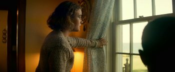 Movie still from “A Quiet Place Part II” (2020), directed by John Krasinski – A woman standing in front of a window looking outside; Medium shot, Low angle