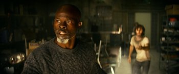 Movie still from “A Quiet Place Part II” (2020), directed by John Krasinski – A man in a gray sweater is looking at the camera; Close Up shot, Low angle