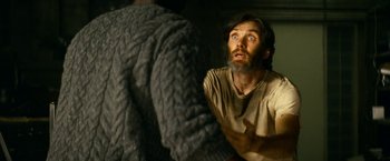 Movie still from “A Quiet Place Part II” (2020), directed by John Krasinski – A man with a long beard and a sweater on; Close Up shot, Over the shoulder angle