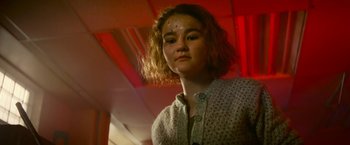 Movie still from “A Quiet Place Part II” (2020), directed by John Krasinski – A young woman is standing in front of a red wall; Close Up shot, Low angle