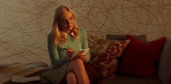 Movie still from “A Rainy Day in New York” (2019), directed by Woody Allen – A woman sitting on a couch writing in a notebook; Medium shot, Over the shoulder angle