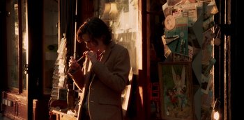 Movie still from “A Rainy Day in New York” (2019), directed by Woody Allen – A man standing in front of a store holding a cell phone to his ear; Medium shot, Over the shoulder angle