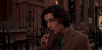 Movie still from “A Rainy Day in New York” (2019), directed by Woody Allen – A man with long brown hair is smoking a pipe; Close Up shot, High angle