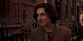 Movie still from “A Rainy Day in New York” (2019), directed by Woody Allen – A man with long brown hair wearing a brown jacket; Close Up shot, Over the shoulder angle