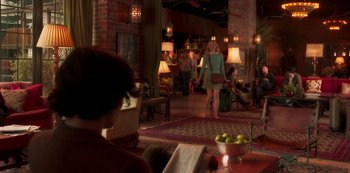 Movie still from “A Rainy Day in New York” (2019), directed by Woody Allen – A woman in a green shirt is walking in a room; Wide shot, Over the shoulder angle