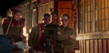 Movie still from “A Rainy Day in New York” (2019), directed by Woody Allen – A group of men standing next to each other on a street; Medium shot, Over the shoulder angle