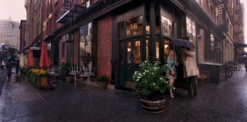 Movie still from “A Rainy Day in New York” (2019), directed by Woody Allen – A woman standing in front of a building on a rainy day; Wide shot, High angle