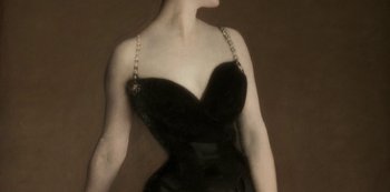 Movie still from “A Rainy Day in New York” (2019), directed by Woody Allen – A woman in a black dress with a chain around her neck; Close Up shot, High angle