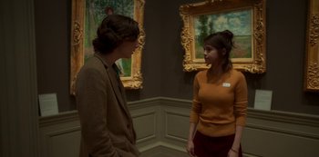 Movie still from “A Rainy Day in New York” (2019), directed by Woody Allen – A man and a woman standing next to each other in front of paintings; Medium shot, Over the shoulder angle