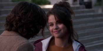 Movie still from “A Rainy Day in New York” (2019), directed by Woody Allen – A young woman smiles at the camera while standing next to a man; Close Up shot, Over the shoulder angle