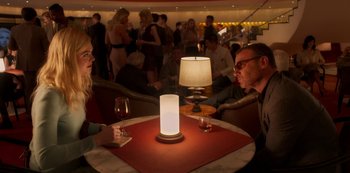 Movie still from “A Rainy Day in New York” (2019), directed by Woody Allen – Two people are sitting at a table with a lamp; Medium shot, Over the shoulder angle