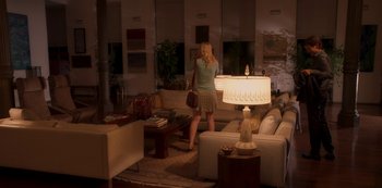 Movie still from “A Rainy Day in New York” (2019), directed by Woody Allen – A woman standing in front of a couch in a living room; Wide shot, High angle
