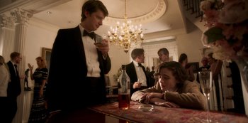 Movie still from “A Rainy Day in New York” (2019), directed by Woody Allen – A group of people sitting at a table with a bottle of wine; Medium shot, Over the shoulder angle