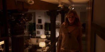 Movie still from “A Rainy Day in New York” (2019), directed by Woody Allen – A woman standing in a living room next to a couch; Wide shot, Low angle