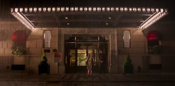 Movie still from “A Rainy Day in New York” (2019), directed by Woody Allen – Two people standing outside of a hotel at night; Extreme Wide shot, Low angle