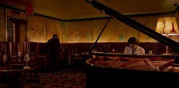 Movie still from “A Rainy Day in New York” (2019), directed by Woody Allen – A man and a woman playing a piano in a room; Wide shot, High angle
