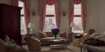 Movie still from “A Rainy Day in New York” (2019), directed by Woody Allen – A living room filled with furniture next to tall windows; Extreme Wide shot, High angle