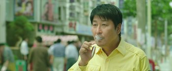 A man in a yellow shirt is brushing his teeth