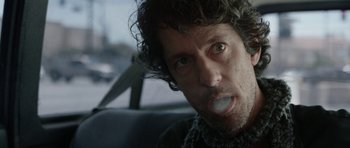Movie still from “A Thousand Junkies” (2017), directed by Tommy Swerdlow – A person in a car eating something; Close Up shot, Over the shoulder angle