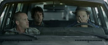 Movie still from “A Thousand Junkies” (2017), directed by Tommy Swerdlow – Two men sitting in the back seat of a car; Close Up shot, Over the shoulder angle