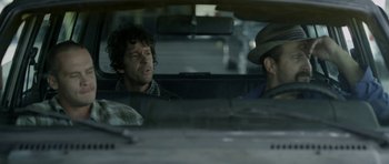 Movie still from “A Thousand Junkies” (2017), directed by Tommy Swerdlow – Two men in the back seat of a car talking; Close Up shot, Over the shoulder angle