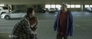 Movie still from “A Thousand Junkies” (2017), directed by Tommy Swerdlow – Three men are standing in a parking garage; Medium shot, Over the shoulder angle