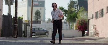 Movie still from “A Thousand Junkies” (2017), directed by Tommy Swerdlow – An older man walking down the street wearing sunglasses; Wide shot, Low angle
