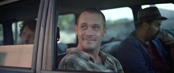 Movie still from “A Thousand Junkies” (2017), directed by Tommy Swerdlow – A man sitting in the back seat of a car; Close Up shot, Low angle