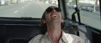 Movie still from “A Thousand Junkies” (2017), directed by Tommy Swerdlow – A man wearing sunglasses sitting in the back of a car; Close Up shot, Low angle