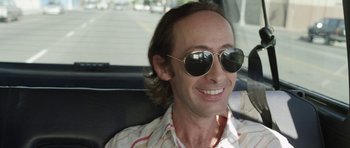 Movie still from “A Thousand Junkies” (2017), directed by Tommy Swerdlow – A man wearing sunglasses sitting in the back of a car; Close Up shot, High angle