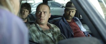 Movie still from “A Thousand Junkies” (2017), directed by Tommy Swerdlow – A group of men sitting in the back of a car; Medium shot, Over the shoulder angle