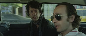 Movie still from “A Thousand Junkies” (2017), directed by Tommy Swerdlow – A man and a woman sitting in the back of a car; Close Up shot, Over the shoulder angle
