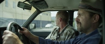 Movie still from “A Thousand Junkies” (2017), directed by Tommy Swerdlow – A man sitting in the driver's seat of a car; Medium shot, Over the shoulder angle