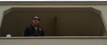 Movie still from “A Thousand Junkies” (2017), directed by Tommy Swerdlow – A man standing on a balcony looking out of a window; Medium shot, Low angle
