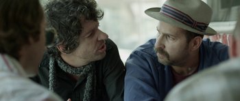 Movie still from “A Thousand Junkies” (2017), directed by Tommy Swerdlow – Two men sitting next to each other in a room; Close Up shot, Over the shoulder angle