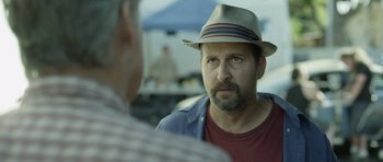 Movie still from “A Thousand Junkies” (2017), directed by Tommy Swerdlow – A man wearing a hat talking to another man; Close Up shot, Over the shoulder angle