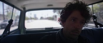 Movie still from “A Thousand Junkies” (2017), directed by Tommy Swerdlow – A man sitting in the back seat of a car looking out the window; Close Up shot, Low angle