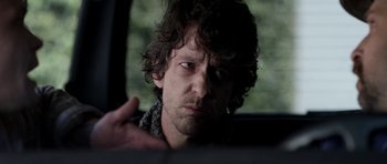 Movie still from “A Thousand Junkies” (2017), directed by Tommy Swerdlow – A person in a car looking at the camera; Close Up shot, Over the shoulder angle