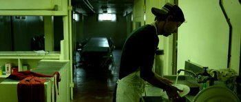 Movie still from “A Thousand Junkies” (2017), directed by Tommy Swerdlow – A man standing in a kitchen preparing a meal; Medium shot, Low angle