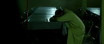Movie still from “A Thousand Junkies” (2017), directed by Tommy Swerdlow – A man in a green coat sleeping on top of a bed; Medium shot, High angle