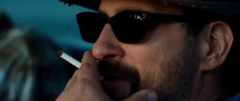 Movie still from “A Thousand Junkies” (2017), directed by Tommy Swerdlow – A person wearing sunglasses; Extreme Close Up shot, Over the shoulder angle