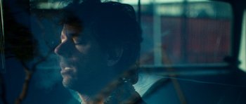 Movie still from “A Thousand Junkies” (2017), directed by Tommy Swerdlow – A man with long hair and a beard is looking out a window; Extreme Close Up shot, Over the shoulder angle