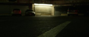 Movie still from “A Thousand Junkies” (2017), directed by Tommy Swerdlow – A car parked on the side of the road at night; Extreme Wide shot, High angle