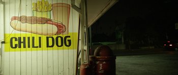 Movie still from “A Thousand Junkies” (2017), directed by Tommy Swerdlow – An image of an outdoor area with a dog sign on the side of the building; Extreme Close Up shot, High angle