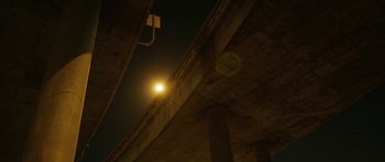 Movie still from “A Thousand Junkies” (2017), directed by Tommy Swerdlow – A street light hanging from the side of a building; Extreme Wide shot, Low angle
