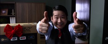 Movie still from “A Very Harold & Kumar Christmas” (2011), directed by Todd Strauss-Schulson – A man in a suit and tie giving a thumbs up; Close Up shot, Low angle