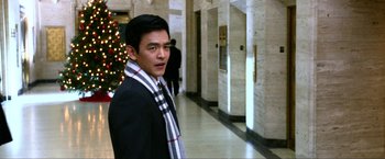 Movie still from “A Very Harold & Kumar Christmas” (2011), directed by Todd Strauss-Schulson – A man in a suit and a scarf standing in front of a christmas tree; Medium shot, Over the shoulder angle